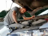 Un hombre intenta reparar su coche.