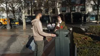 Dos jóvenes depositando un papel en una papelera de la Plaza Nueva, en el centro de Sevilla