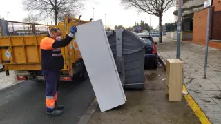 Un trabajador de Lipasam recoge muebles depositados junto a un contenedor